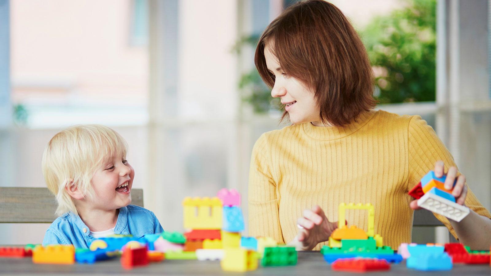 preschool teacher and young child playing with blocks