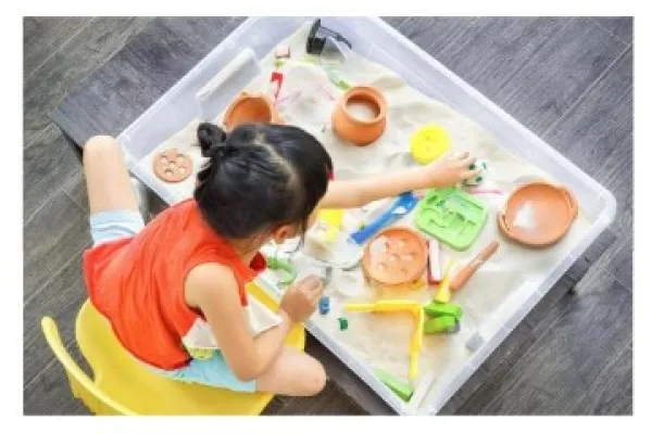 A young girl playing at a sensory table